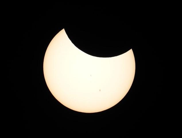 Partial solar eclipse with moon eclipsing the top part of the sun.