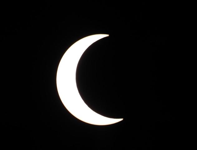 Partial solar eclipse with moon covering the majority of the sun from the left.