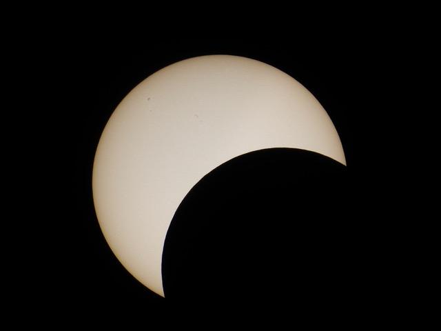 Partial solar eclipse with moon covering part of the sun from the bottom left.