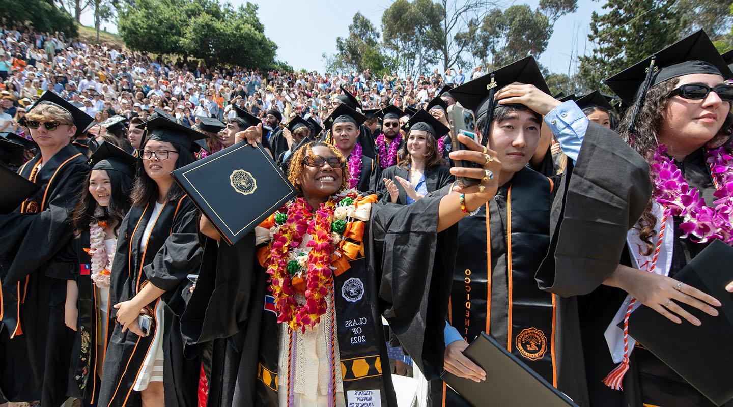 Proud graduates holding up their degrees on Commencement Day