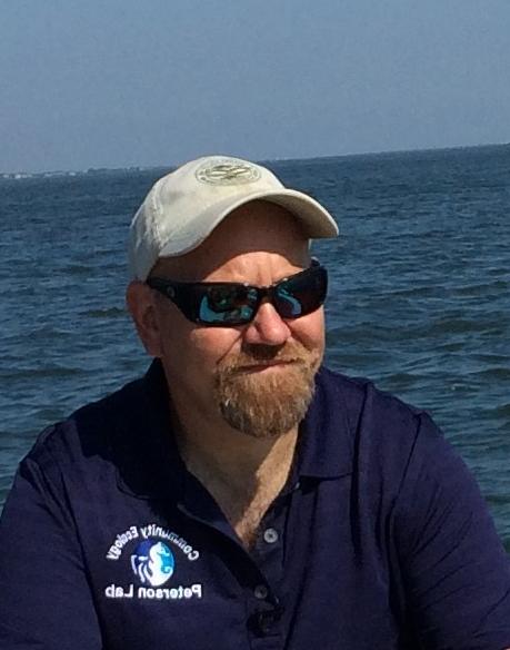 Man with hat and sunglasses in front of water