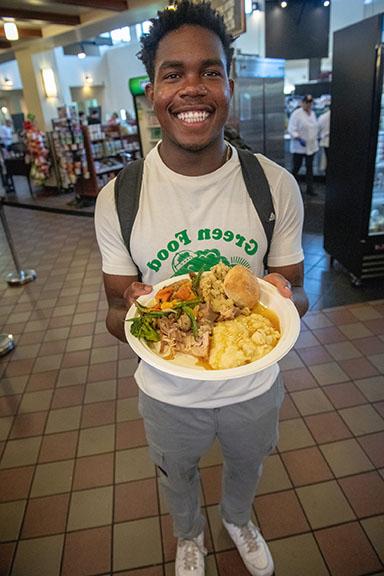 A student holding up a plate of food in the Marketplace