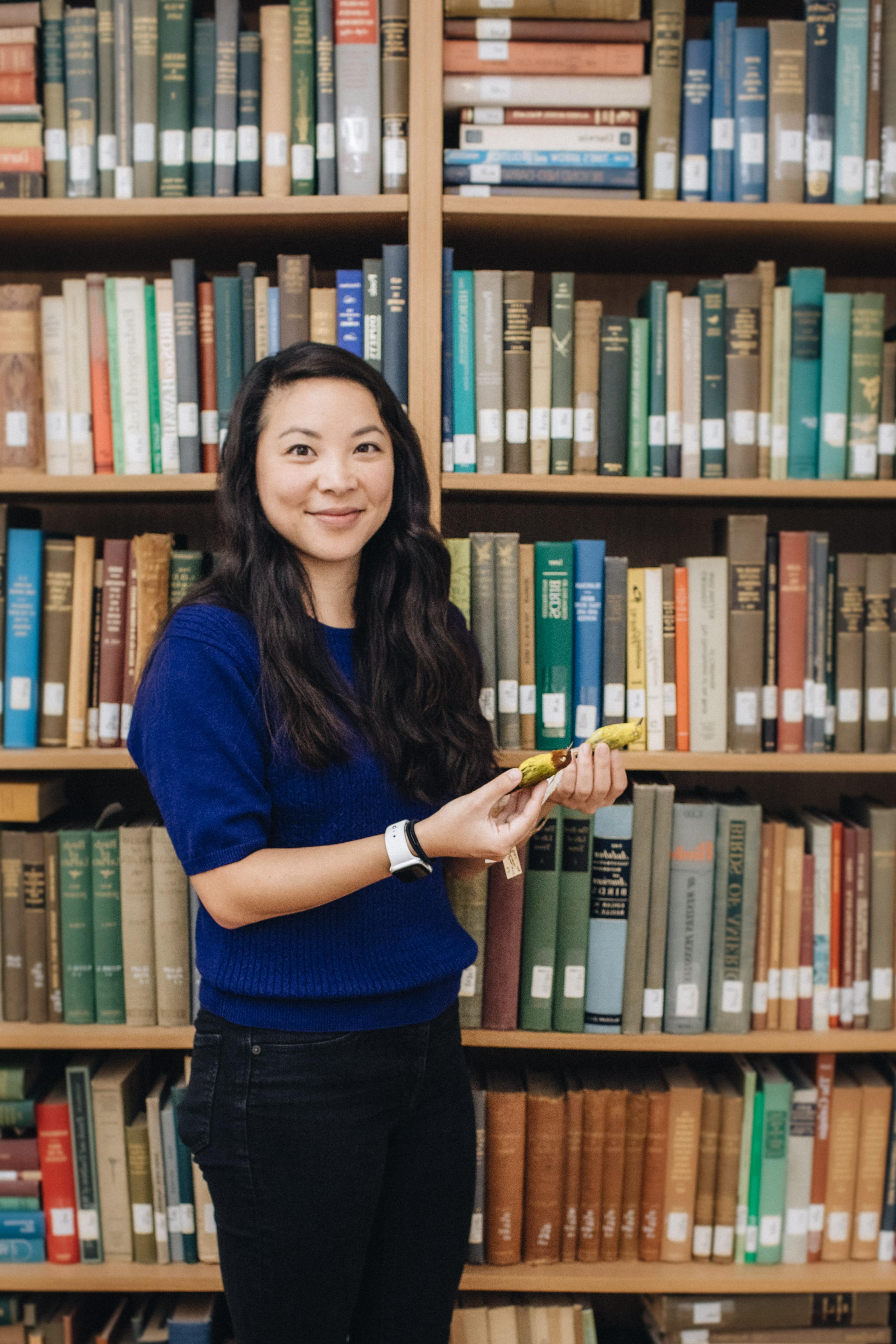 Whitney Tsai Nakashima in front of bookshelf holding birds