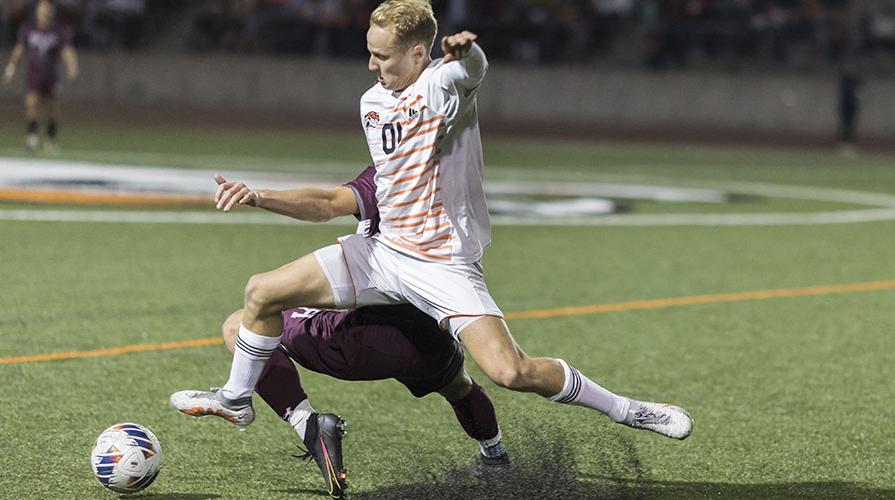 An Oxy soccer player hangs suspended in the air as he goes to kick the ball