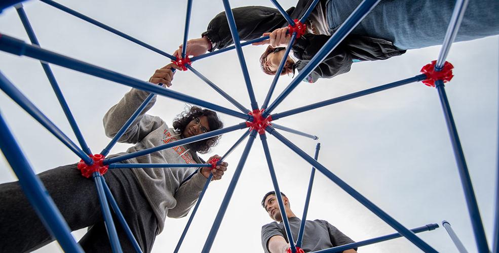 three 学生 shot from below, constructing the Oxyhedron structure