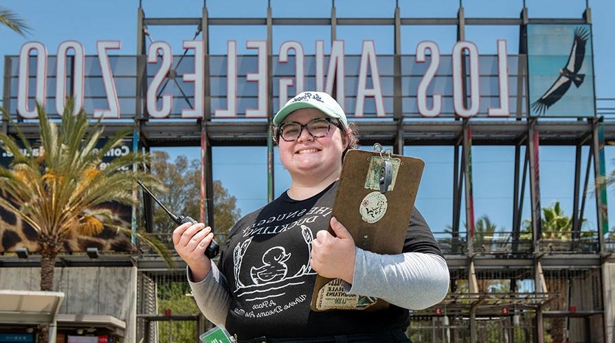 Oxy student intern with a clipboard in front of the 洛杉矶 Zoo sign