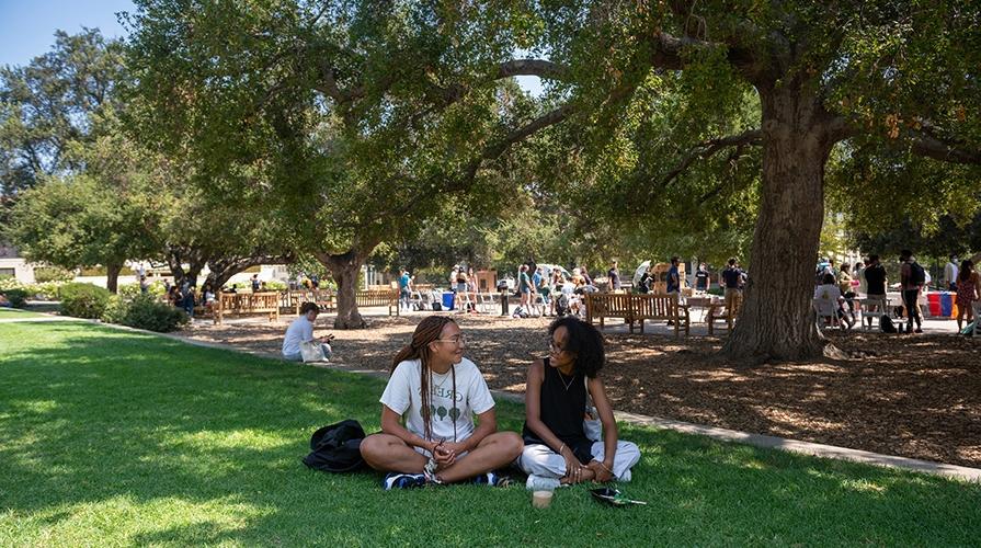 Two students sitting on the lawn of the Quad