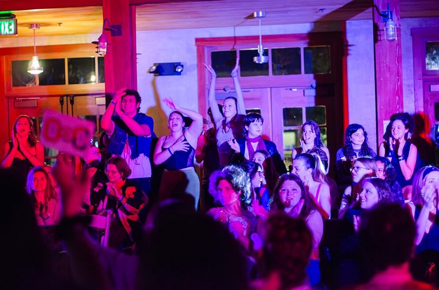 Group of student clapping in a dim room with pink light