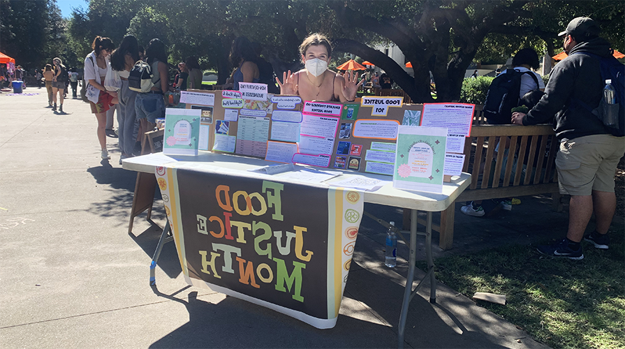 student staffing the Food 正义 Month table on the quad