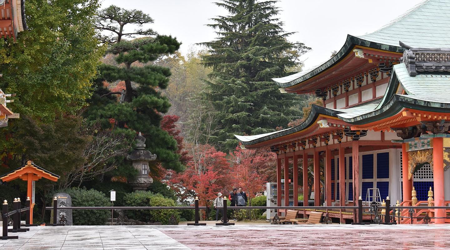 A view of the red Hiroshima temple with pine trees in the background