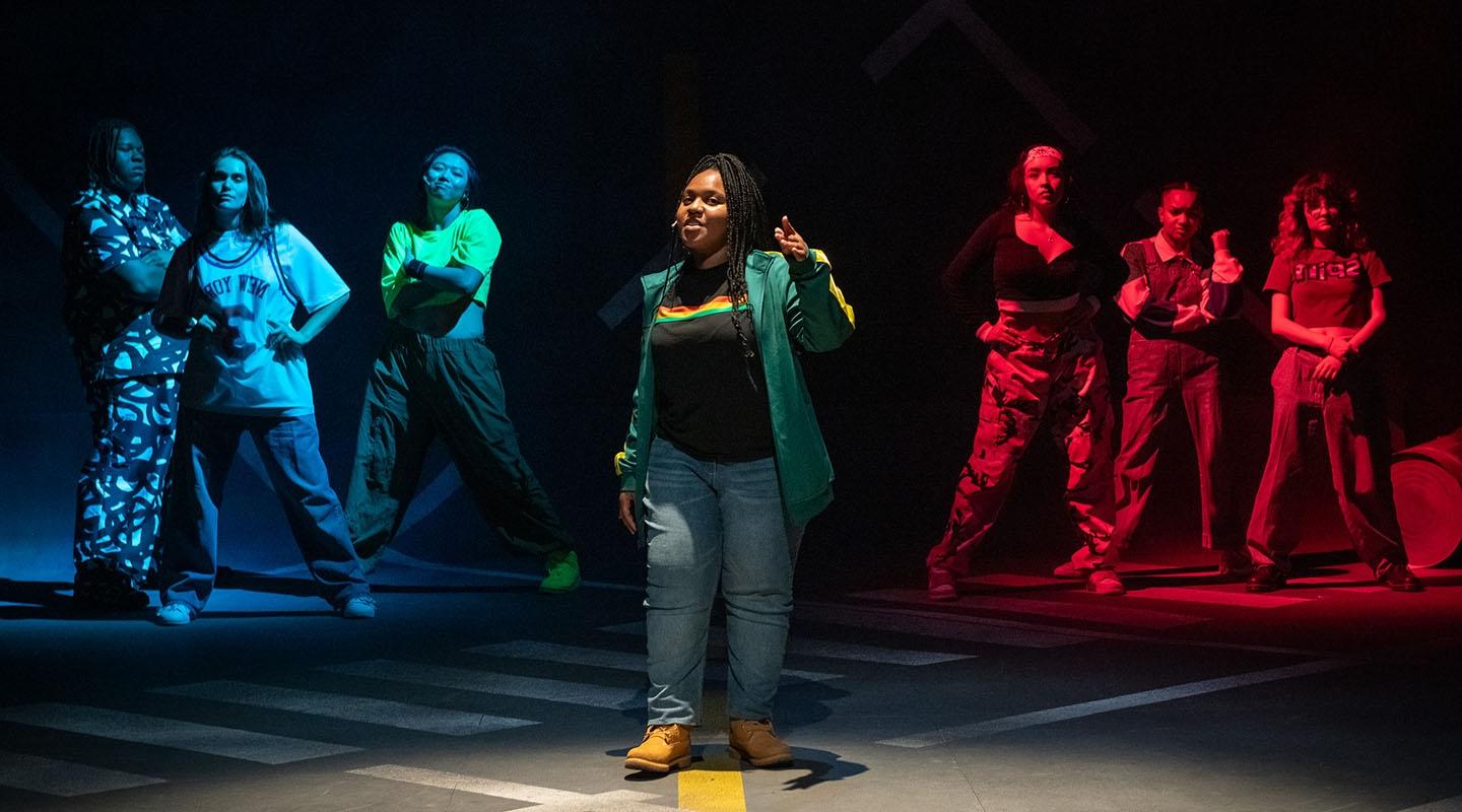 students in hip-hop clothing stand in a formation on the Keck Theater stage