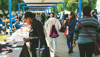 A group of people at an informational fair, looking at tables and talking to others