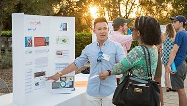 Student gestures to presentation board as he explains InternLA experience