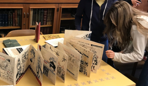 Students examine an old printed brochure from Oxy's special collection