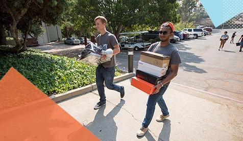 students carrying boxes on campus