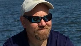 Man with hat and sunglasses in front of water