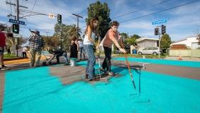 Two students painting the asphalt on Yosemite Way a bright teal color