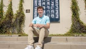 James Steinberger '25 sits on the steps in front of Haines Hall with a blue shirt.