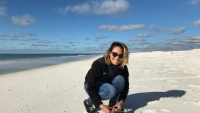 Dr. Caitlin Fong crouching on a beach