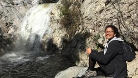 Roshni Katrak-Adefowora sitting in front of a waterfall