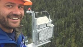 Troy Magney above trees with hard hat and equipment