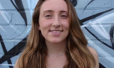 brenna knapp in front of a painted brick wall