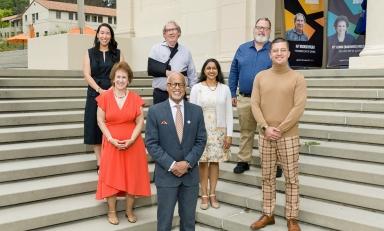 A group of alumni and President Elam stand in formation on some steps