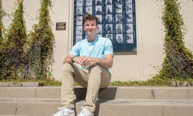 James Steinberger '25 sits on the steps in front of Haines Hall with a blue shirt.